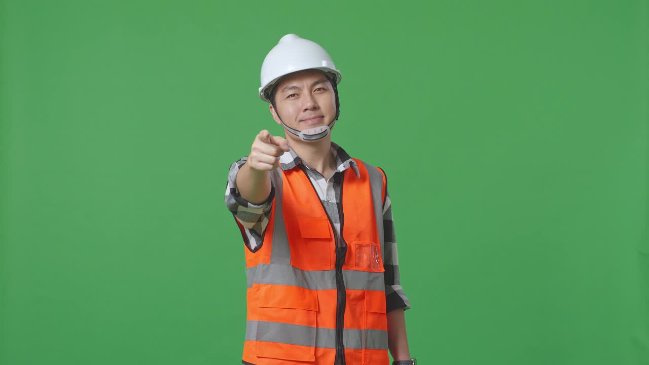 Asian Male Engineer With Safety Helmet Smiling And Touching His Chest Then Pointing At You While Standing In The Green Screen Background Studio