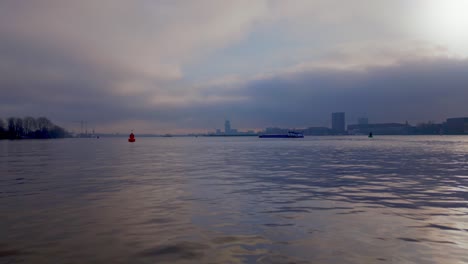 foggy environment over the north sea canal with a tanker ship passing by, amsterdam city