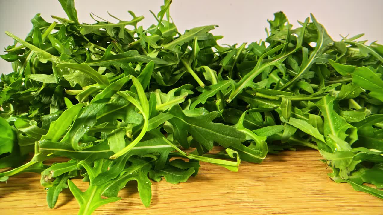 木のテーブルに新鮮なルッコラを添えた葉物野菜のトラッキングショット。