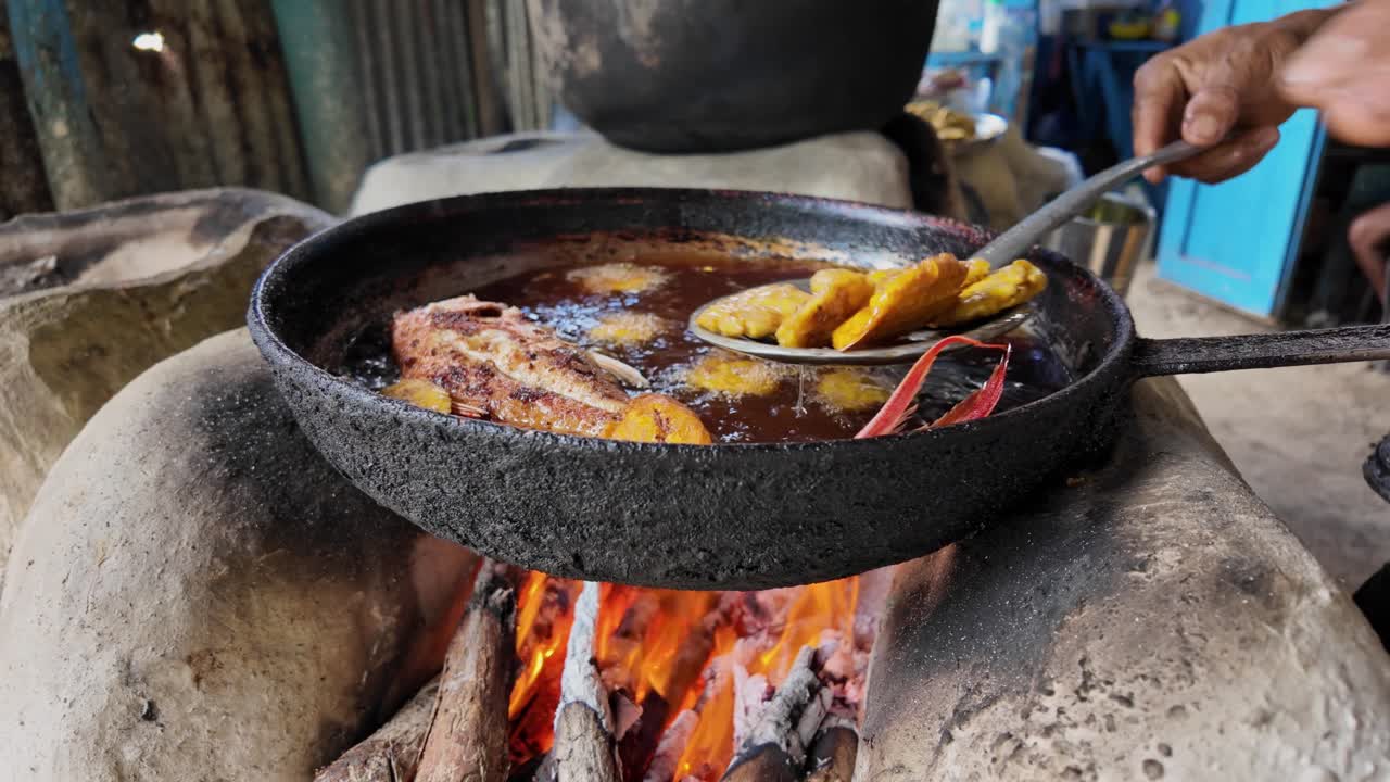 Serving fried fish with fried plantains from a rustic stove on a Dominican beach