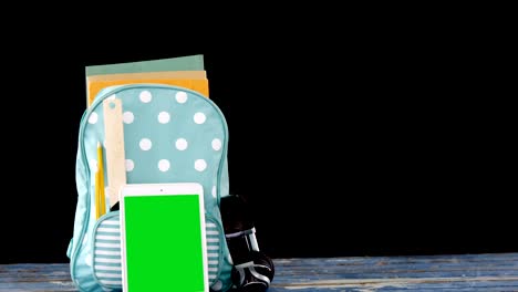 bolso escolar y tableta digital dispuestos en la mesa