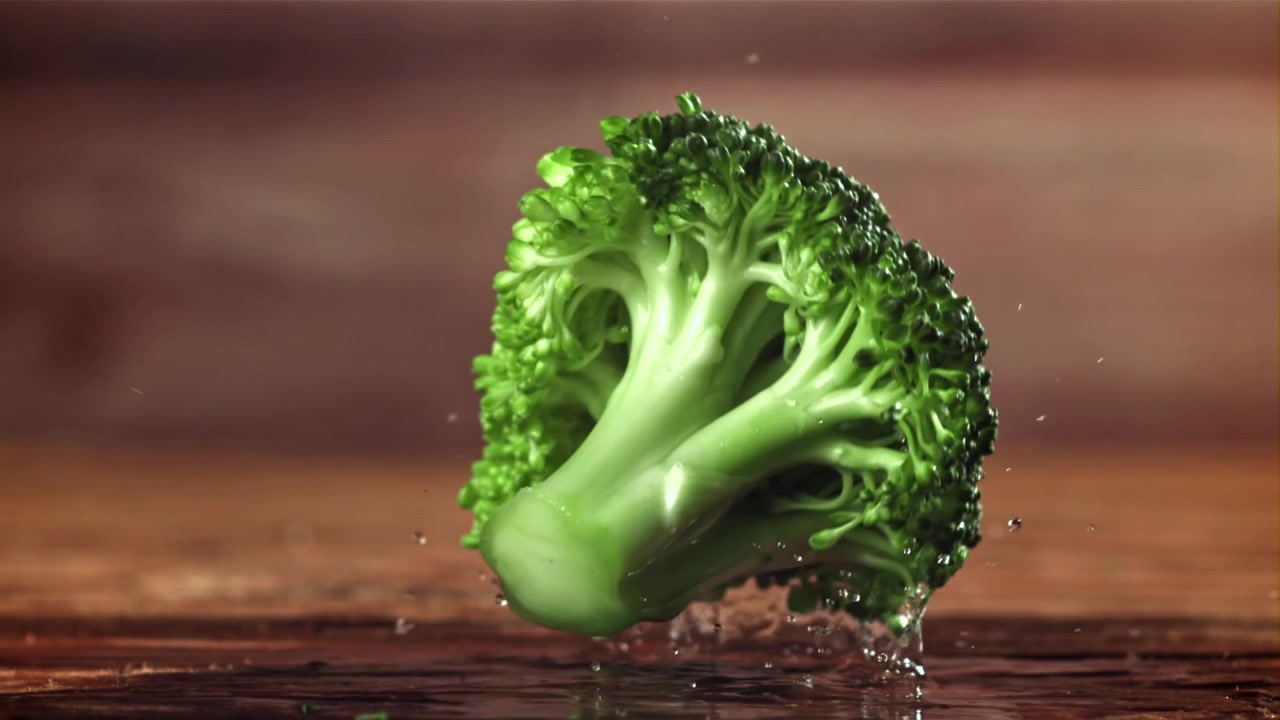 Fresh Broccoli Falling and Splashing on Wet Wooden Surface in Slow Motion