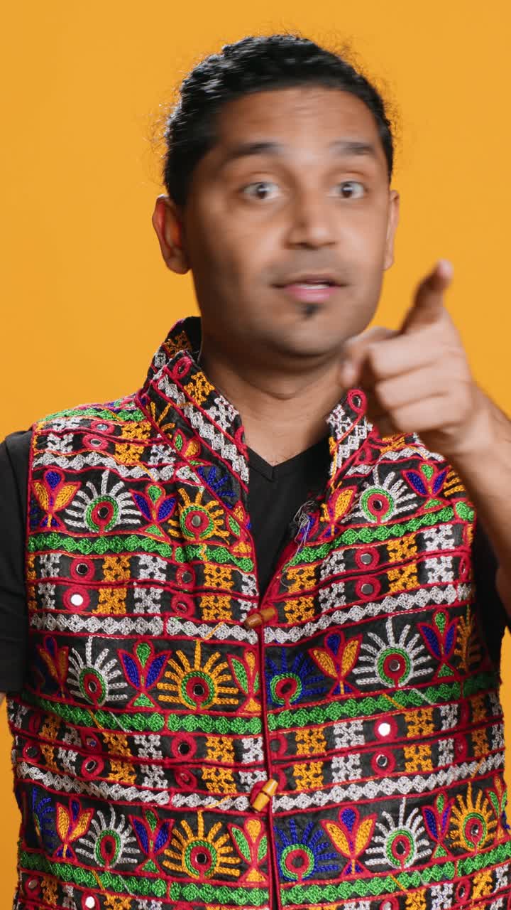 Expressive Man in Colorful Vest Pointing at Camera