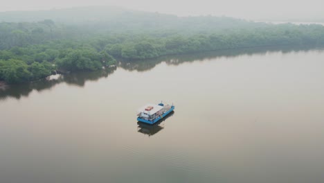 ship boat in still river india goa divar island panjim drone morning fog sunset foggy weather orbital shot