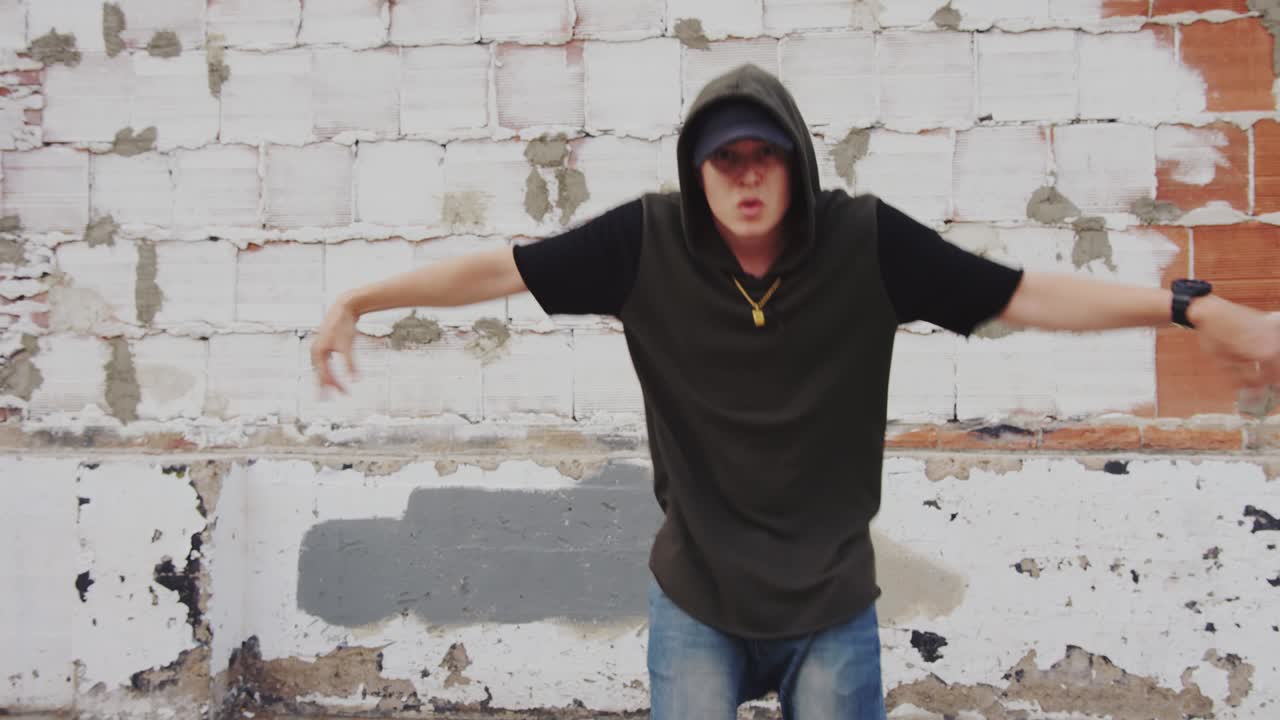 hombre de hip hop bailando afuera en la ciudad frente a una pared de ladrillo