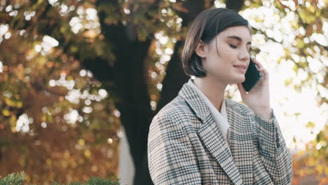 stylish businesswoman using smartphone outdoor.