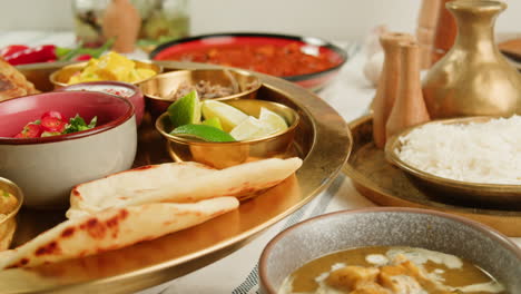 assorted indian sri-lanka food set on wooden background. dishes and appetisers of indeed cuisine, rice, lentils, paneer, samosa, spices, masala. bowls and plates with indian food top view chicken. high quality 4k footage