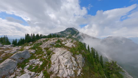 drone flying over rocky mountain with green pine trees in squamish town, british columbia, canada