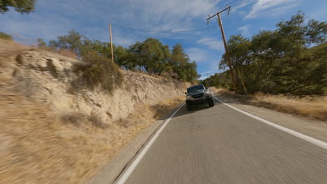 un dron acrobático fpv disparó con un coche de policía persiguiendo a lo largo de una carretera rural
