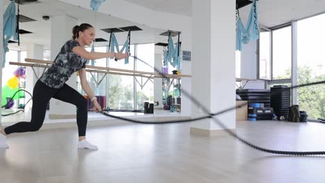woman working out with battle ropes in a gym