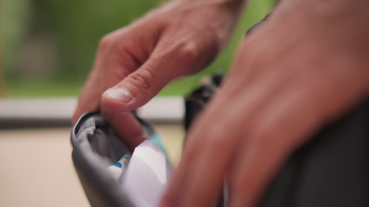 Man Retrieves Item, Person Unzips Bag To Access Item, Man Opens Bag To Retrieve Hydration Item Carefully, Individual On Park Bench Carefully Unzips And Retrieves Small Gear Item For Hydration