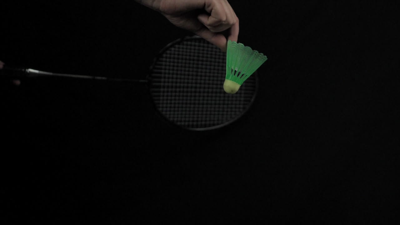 검은색 배경으로 느린 동작으로 배드민턴 라켓으로 제공 된 버디의 클로즈업