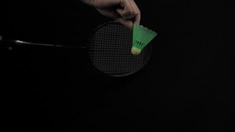 close up of birdie served with badminton racket in slow motion with black background