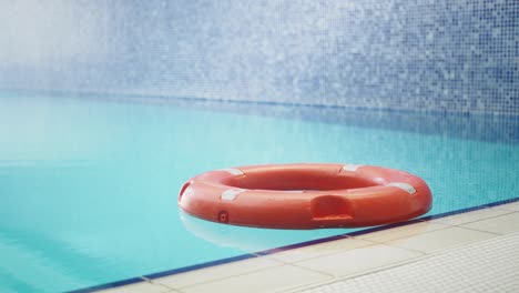 a red life preserver floats in a blue swimming pool