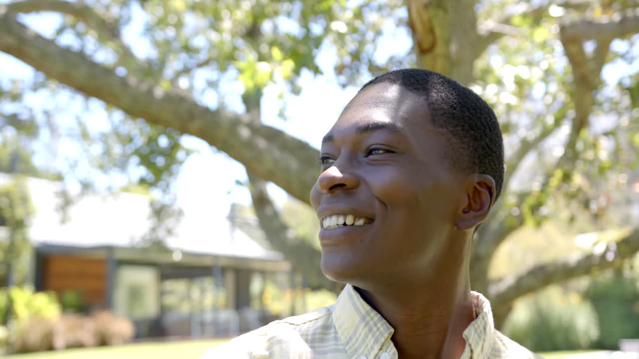 A young African American male smiling, looking away outdoors, at home