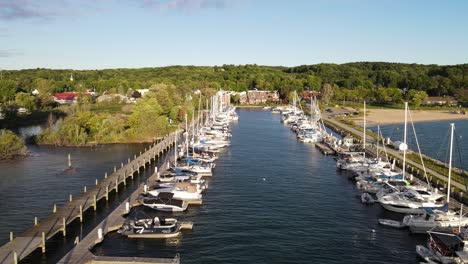 sunny day in suttons bay pier with many sailboats moored, aerial drone view