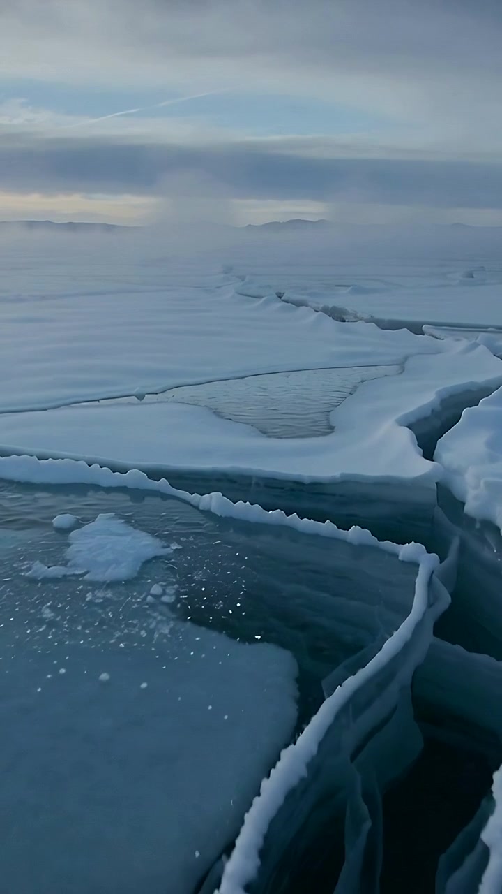 Vertical video: Following low cam moving along cracked floe in Arctic, showing leads and horizon