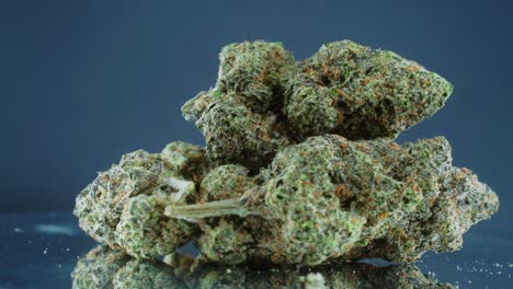 grayish green dried marijuana buds - close up concept shot, pile of dried marijuana plants, orange trichomes strains, on a reflecting rotating stand, studio lights, slow motion, 4k video 2