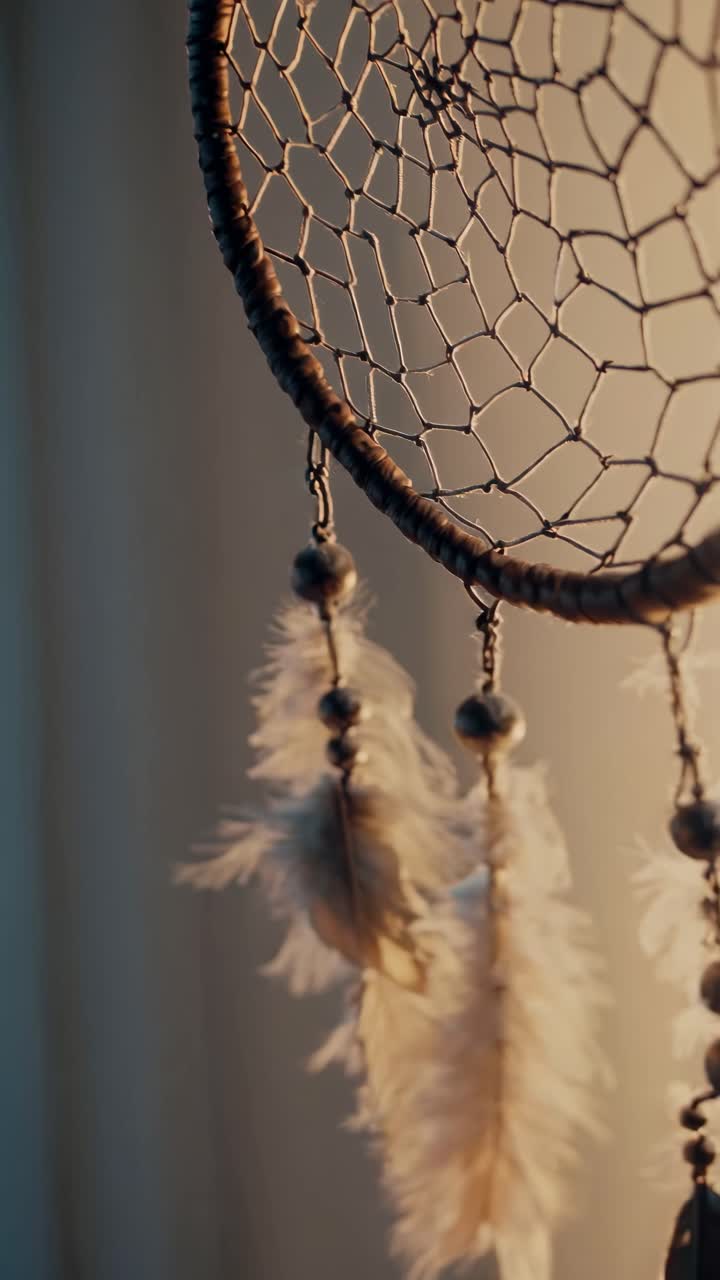 Close-up video of a dreamcatcher with soft lighting, showcasing intricate details and feathers, shot