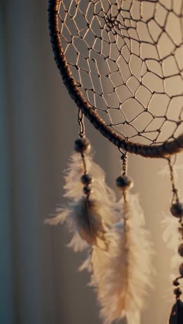 close-up video of a dreamcatcher with soft lighting, showcasing intricate details and feathers, shot