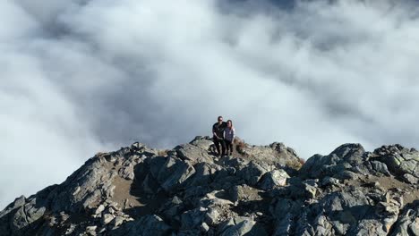 couple hiking to the mountain peak above the clouds