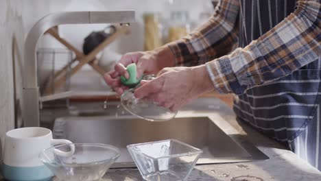 hands of caucasian man washing dishes in kitchen, slow motion