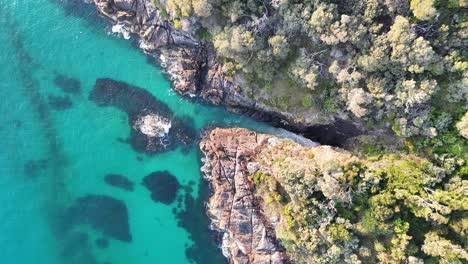 breathtaking aerial view of a pristine turquoise cove surrounded by rugged coastal terrain and lush greenery