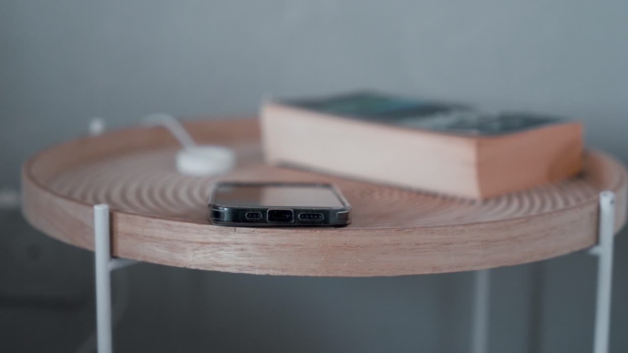 Man hand grabbing smartphone on table nightstand next to bed, reaching to mobile phone in morning evening living in social digital world.