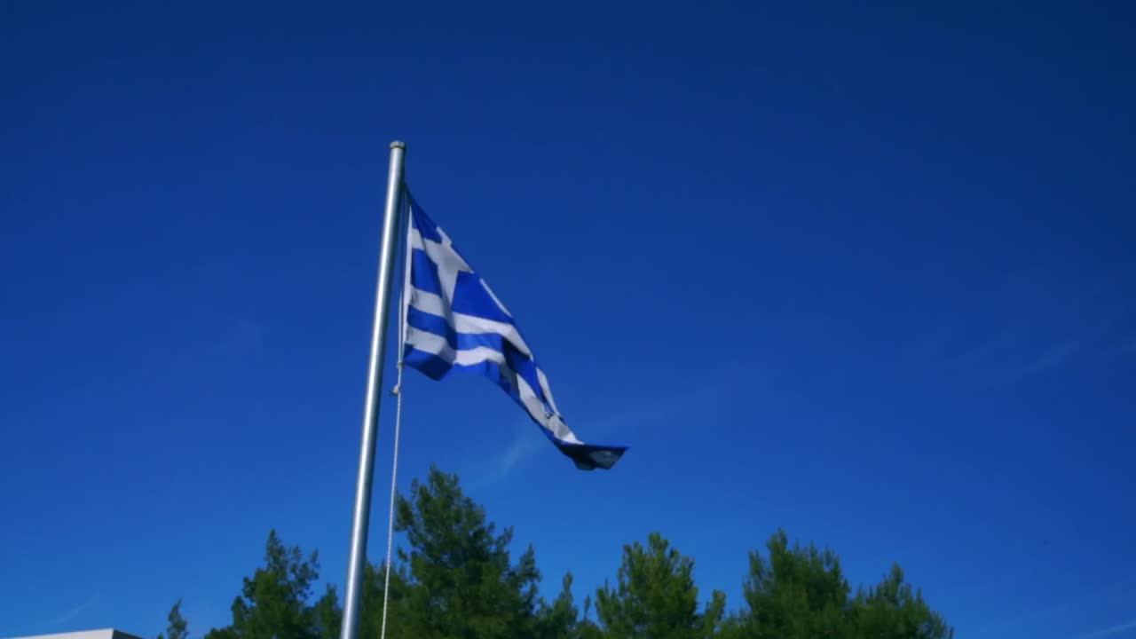 Græsk flag vajer med klar blå himmel som baggrund. SLOWMOTION