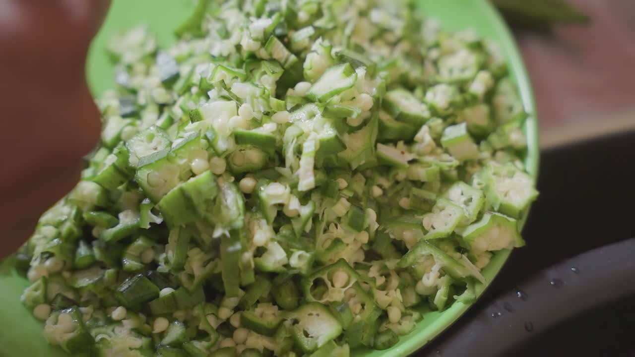 Closeup of chopped green okra with seasoning. Market scene featuring vibrant chopped okra in plastic container. Detailed image of vibrant green chopped okra with seasoning in market setting