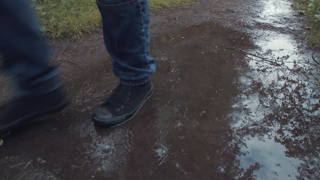 People Walking Through a Puddle on a Rainy Day in the Woods