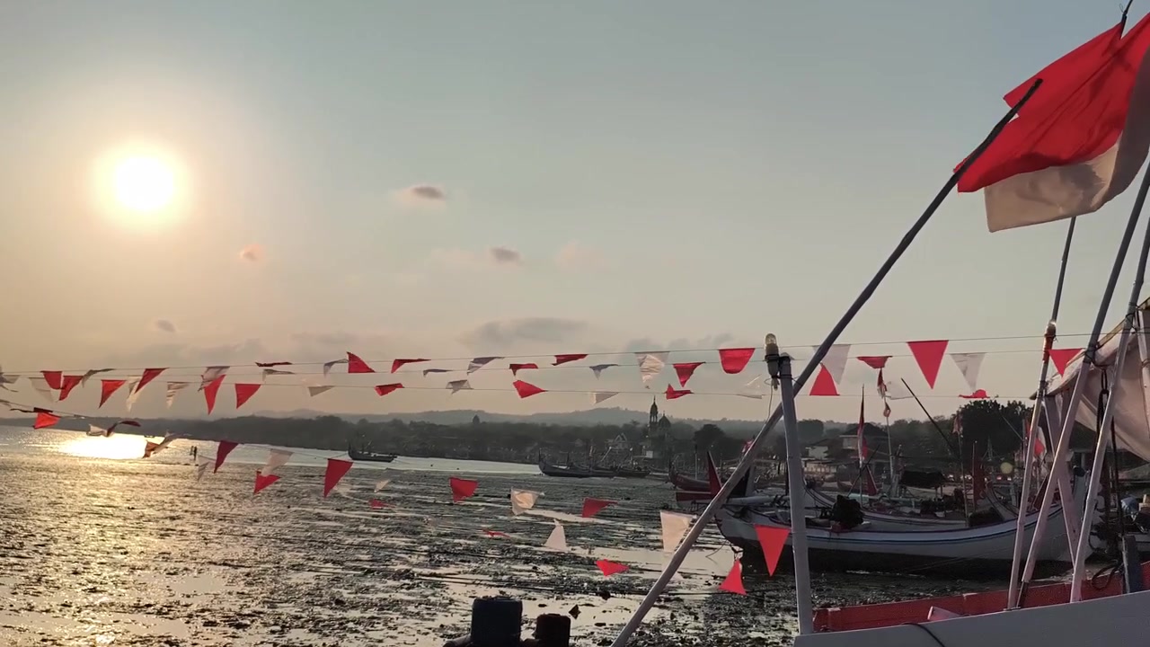 Barche da pesca decorate con bandiere rosse e bianche al tramonto.