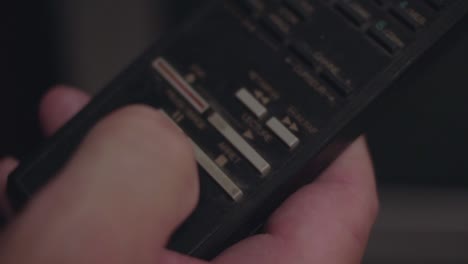 primer plano de un dedo presionando el botón de reproducción en un antiguo control remoto de televisión