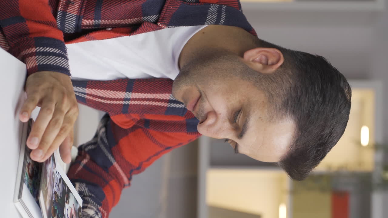 가족 앨범을 보는 남자의 수직 비디오는 우울합니다.