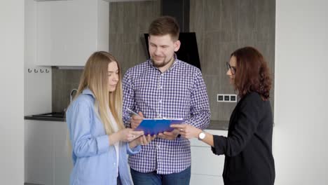 a young married couple will sign the documents on the receipt of the apartment with design repair