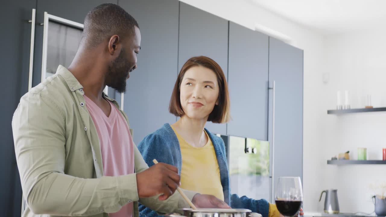 Video di una coppia felice e mista che prepara del cibo insieme in cucina, a casa.