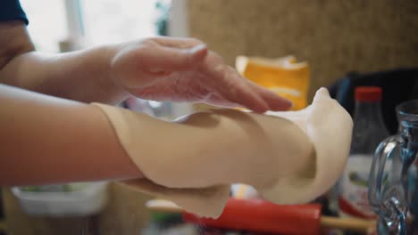 una mujer sostiene un gran panqueque hecho de masa en sus manos y lo da la vuelta. disparando una prueba en las manos de un primer plano