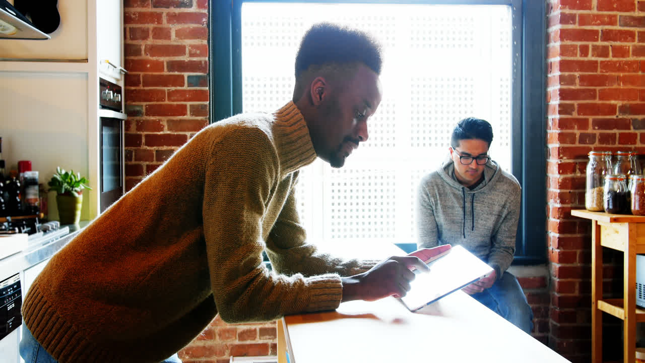 Gay couple using digital tablet and mobile phone