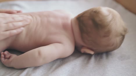 infant boy lies on baby table and nurse makes massage