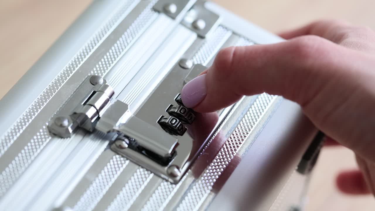 Female hand opens silver briefcase using combination lock
