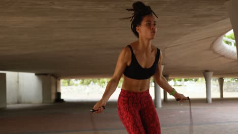 Front-view-of-young-African-American-woman-exercising-with-skipping-rope-in-the-city-4k