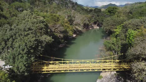 bright yellow bridge crosses semuc champey river in guatemala jungle