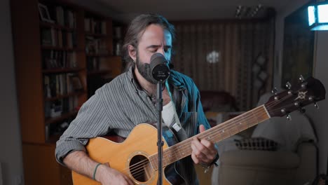 man singing and playing acoustic guitar at home