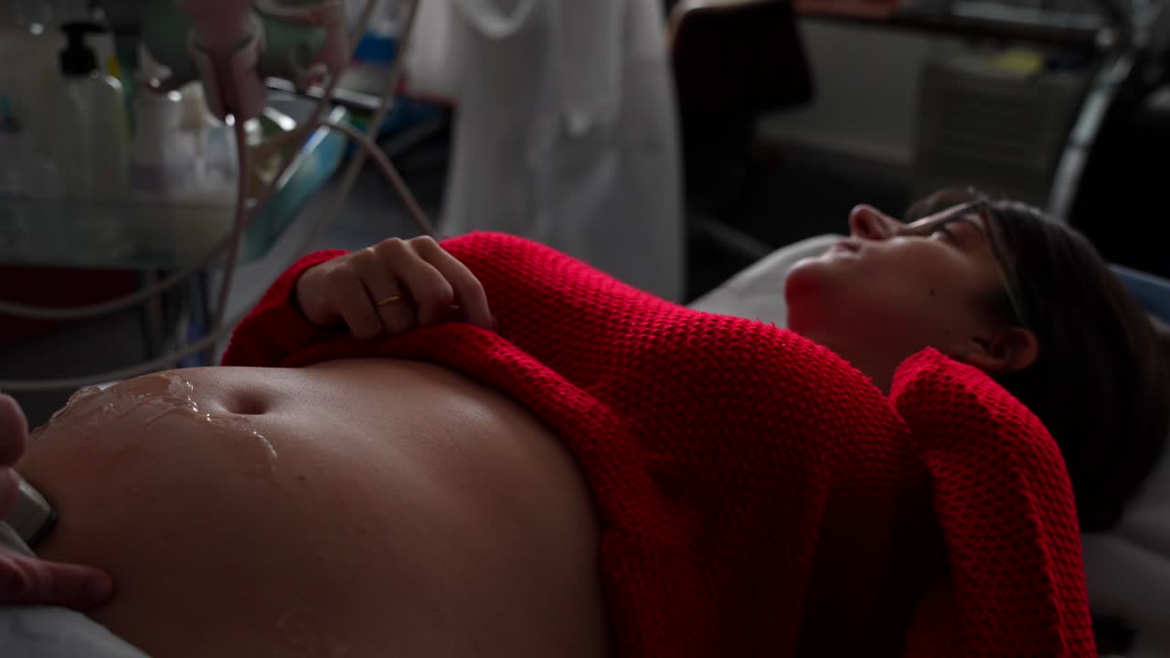 Sedyede gergin hamile kadın ve doktorun ultrasonla muayene etmesi.