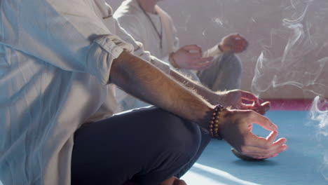hombres meditando con humo de palos de incienso a su alrededor