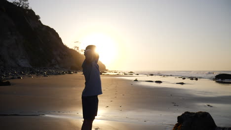 a strong man in silhouette breathing and stretching after an early morning run and workout on the beach at sunrise in santa barbara, california slow motion