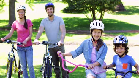 smiling family on a bike ride in the park together