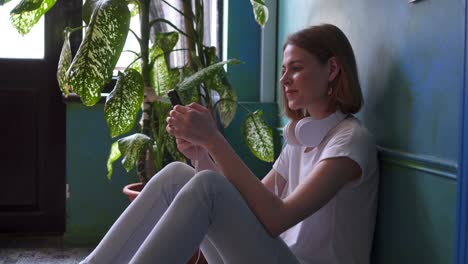 young happy girl sitting on floor and listening music