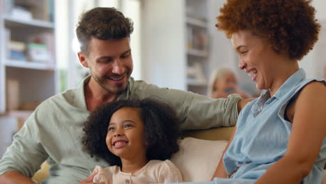 daughter sitting with on sofa at home with loving parents