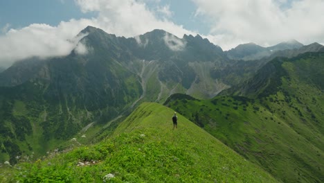 a woman hikes a scenic green mountain ridge with stunning views of the austrian alps